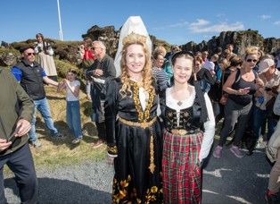 Edda Björg fjallkona og Svana Björg Eiríksdóttir í peysufötum standa við Lögberg í Almannagjá. Hópur fólks í kringum þau