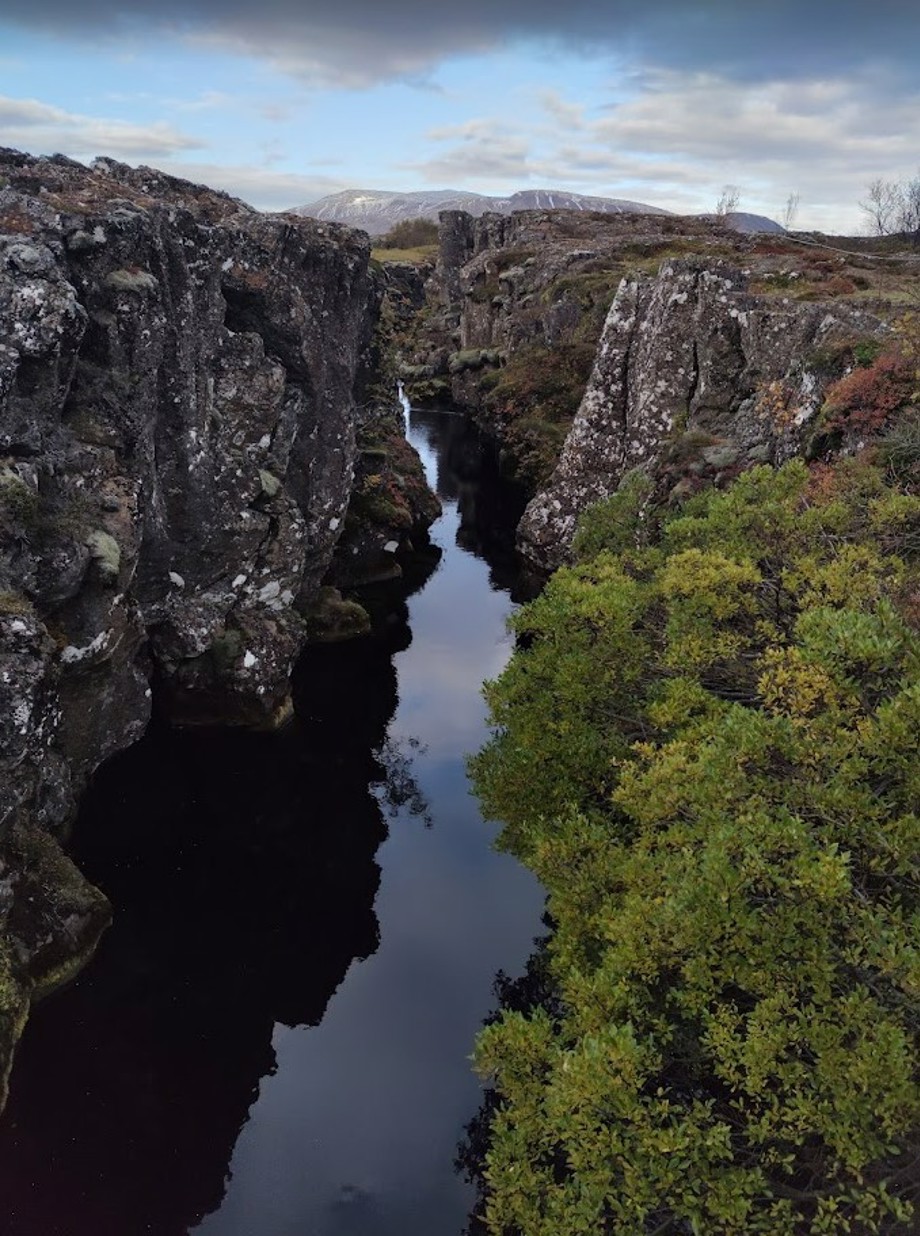 The Nikulásargjá crevasse and spring water, seen from a bridge crossing it. Ármannsfell mountain in the background.